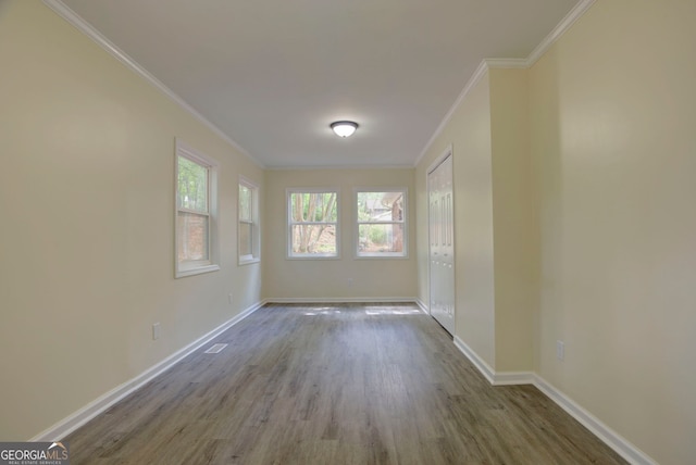 empty room with baseboards, ornamental molding, and wood finished floors
