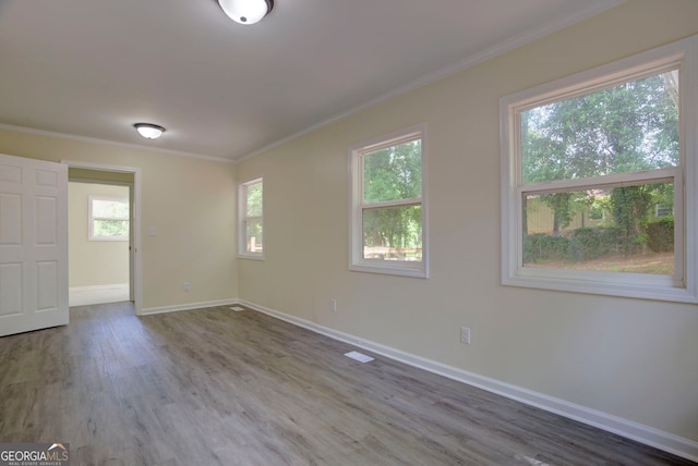 unfurnished room with crown molding, baseboards, visible vents, and wood finished floors