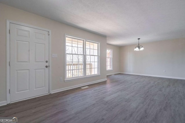 entryway featuring visible vents, baseboards, a textured ceiling, dark wood finished floors, and a notable chandelier