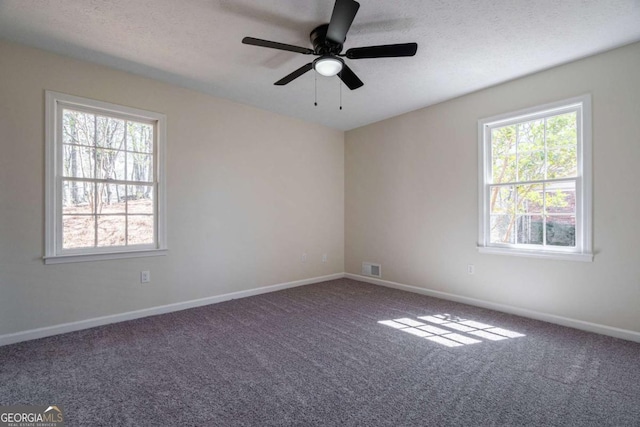 carpeted spare room with baseboards, a ceiling fan, and a wealth of natural light