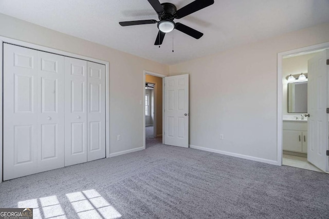 unfurnished bedroom with baseboards, a sink, carpet, and a closet