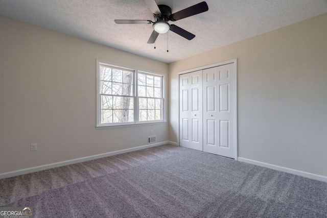 unfurnished bedroom with visible vents, a closet, baseboards, a textured ceiling, and carpet flooring