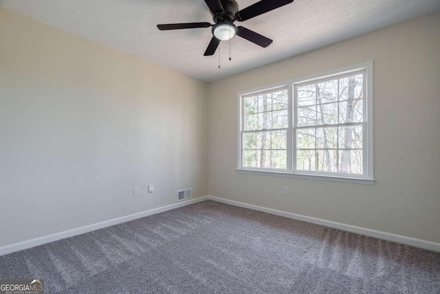 carpeted spare room with baseboards, ceiling fan, a textured ceiling, and visible vents