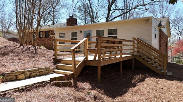 back of property with brick siding, a wooden deck, stairs, and a chimney