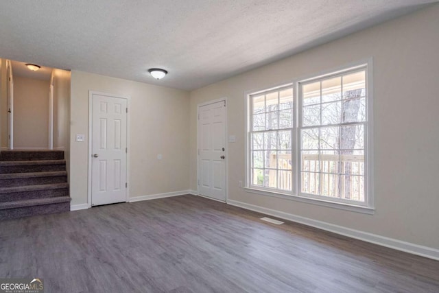 foyer entrance featuring visible vents, wood finished floors, baseboards, stairway, and a textured ceiling