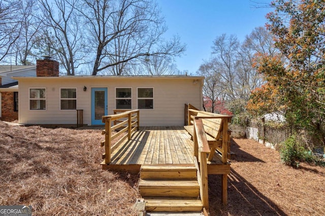 rear view of house featuring a wooden deck and a chimney