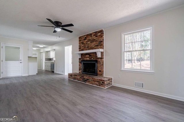 unfurnished living room with a ceiling fan, dark wood-style flooring, visible vents, crown molding, and baseboards