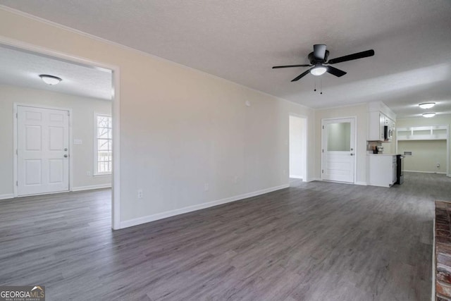 unfurnished living room featuring a ceiling fan, a textured ceiling, crown molding, dark wood finished floors, and baseboards