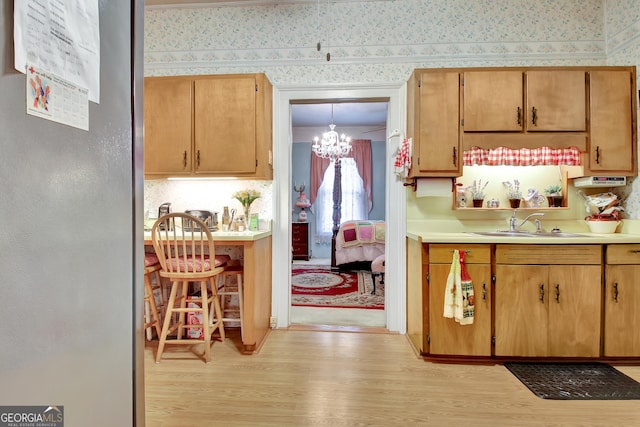 151 Flat Shoals Rd, Woodbury, GA 30293 - kitchen featuring wallpapered walls, light countertops, light wood-style flooring, a notable chandelier, and a sink