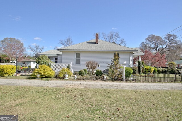151 Flat Shoals Rd, Woodbury, GA 30293 - view of side of home featuring a shingled roof, a yard, fence, and a chimney