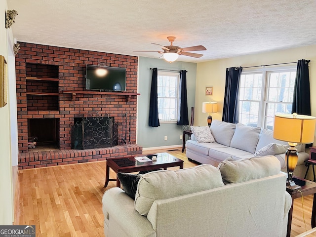 285 W0Lf Den Rd, Royston, GA 30662 - living room with wood finished floors, ceiling fan, a textured ceiling, a fireplace, and baseboards