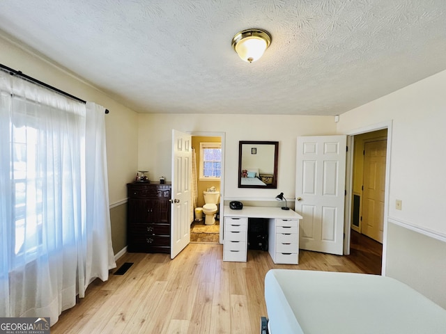 285 W0Lf Den Rd, Royston, GA 30662 - bedroom featuring light wood-type flooring, baseboards, a textured ceiling, and connected bathroom