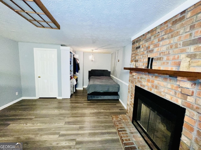 285 W0Lf Den Rd, Royston, GA 30662 - bedroom featuring wood finished floors, baseboards, a textured ceiling, and a fireplace