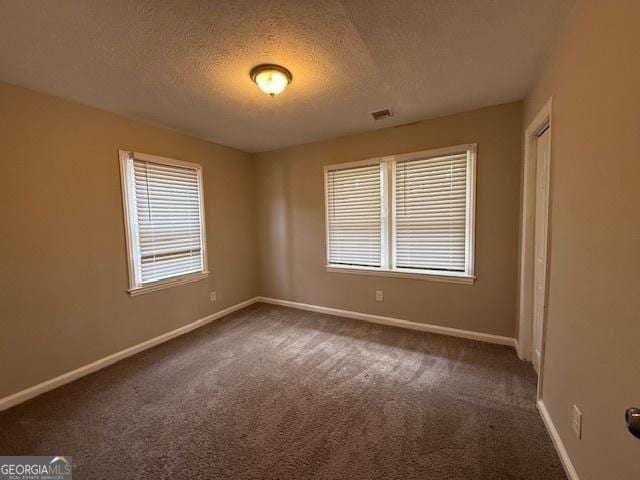1643 Columbia Dr, Decatur, GA 30032 - empty room with visible vents, a textured ceiling, baseboards, and dark colored carpet
