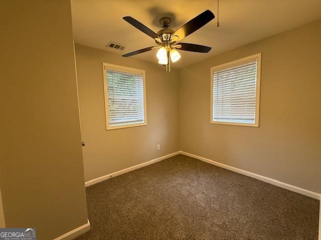 192 Margaret St, Fairburn, GA 30213 - empty room with baseboards, visible vents, dark colored carpet, and a healthy amount of sunlight