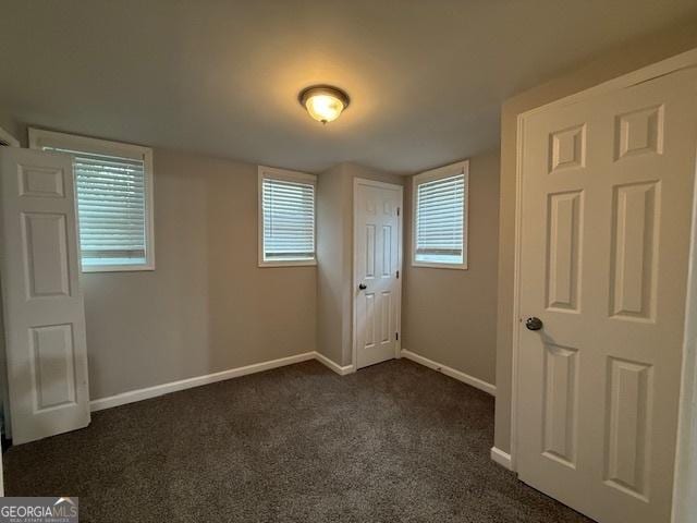 192 Margaret St, Fairburn, GA 30213 - unfurnished bedroom with multiple windows, baseboards, and dark colored carpet