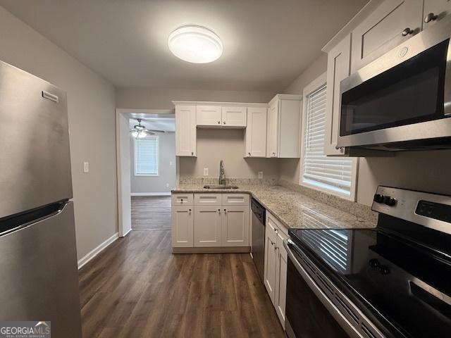 192 Margaret St, Fairburn, GA 30213 - kitchen with dark wood-type flooring, light stone countertops, white cabinets, stainless steel appliances, and a sink