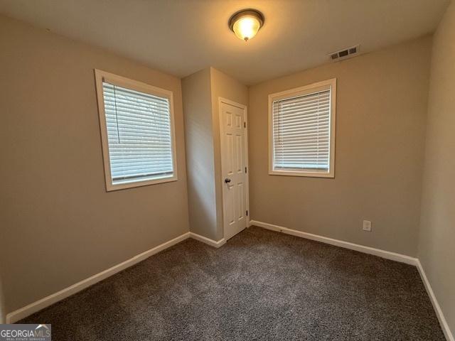 192 Margaret St, Fairburn, GA 30213 - spare room with visible vents, dark carpet, and baseboards