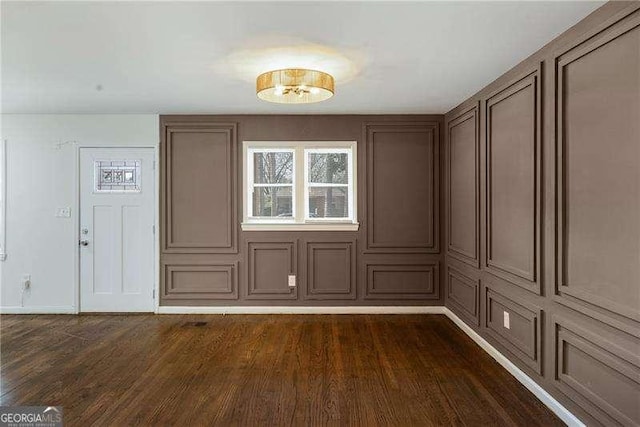 unfurnished dining area with dark wood-type flooring and baseboards