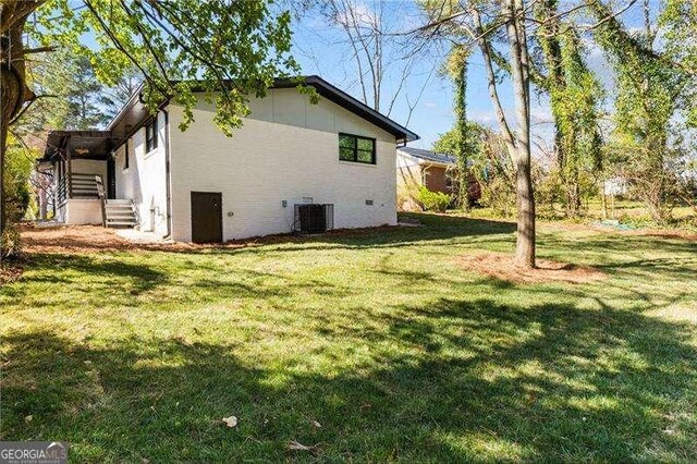 view of side of property featuring cooling unit and a lawn