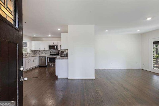 kitchen featuring dark wood-type flooring, white cabinets, tasteful backsplash, and appliances with stainless steel finishes