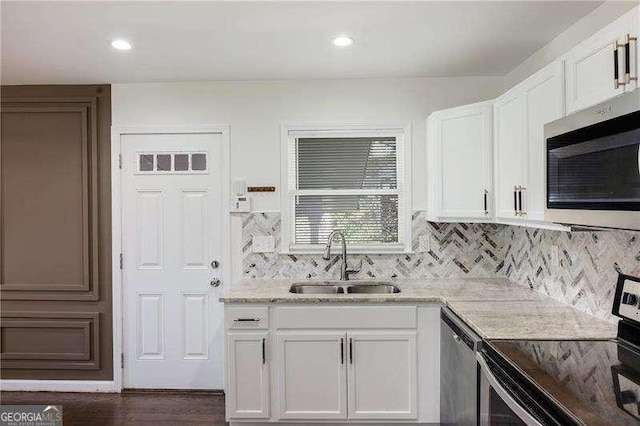 kitchen featuring a sink, white cabinetry, stainless steel appliances, decorative backsplash, and light stone countertops