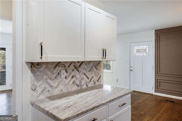 kitchen with dark wood-type flooring, light stone counters, decorative backsplash, a wealth of natural light, and white cabinets