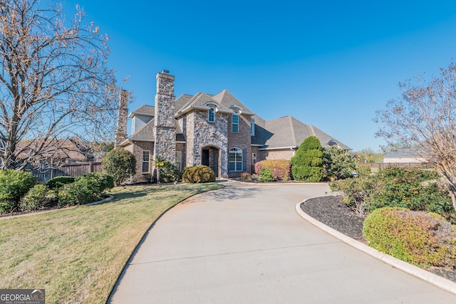 view of home's exterior featuring a lawn, stone siding, fence, concrete driveway, and a shingled roof