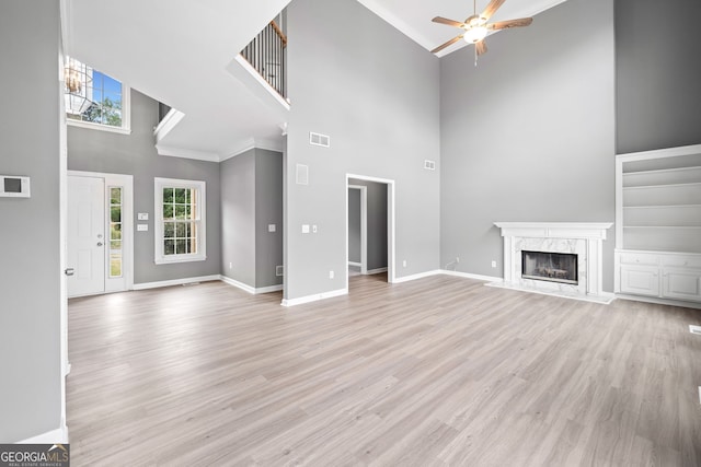 unfurnished living room with visible vents, ceiling fan, a high ceiling, and a healthy amount of sunlight