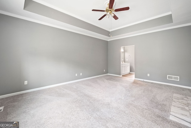 carpeted spare room with a tray ceiling, crown molding, a ceiling fan, and visible vents