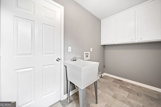 laundry room featuring washer hookup, baseboards, and cabinet space