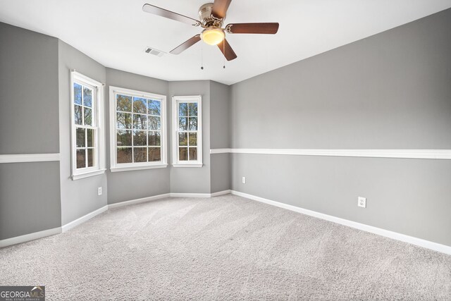 empty room featuring ceiling fan, visible vents, baseboards, and carpet