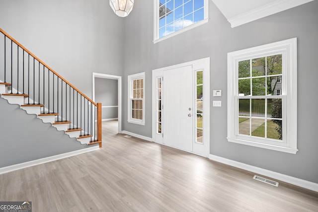 foyer featuring visible vents, baseboards, stairway, and wood finished floors