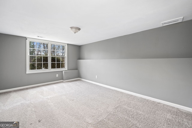 empty room with carpet, visible vents, and baseboards