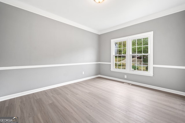 unfurnished room with crown molding, visible vents, baseboards, and wood finished floors
