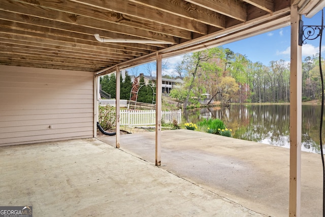 view of patio with fence and a water view