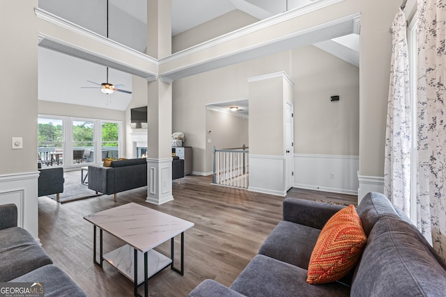living area with wainscoting, wood finished floors, a towering ceiling, and ceiling fan