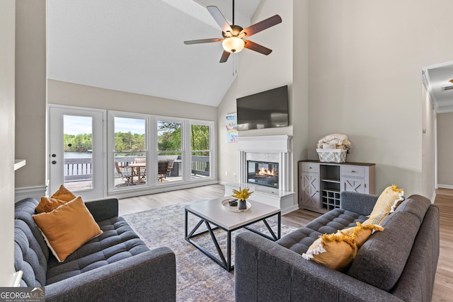 living area featuring baseboards, wood finished floors, ceiling fan, high vaulted ceiling, and a high end fireplace