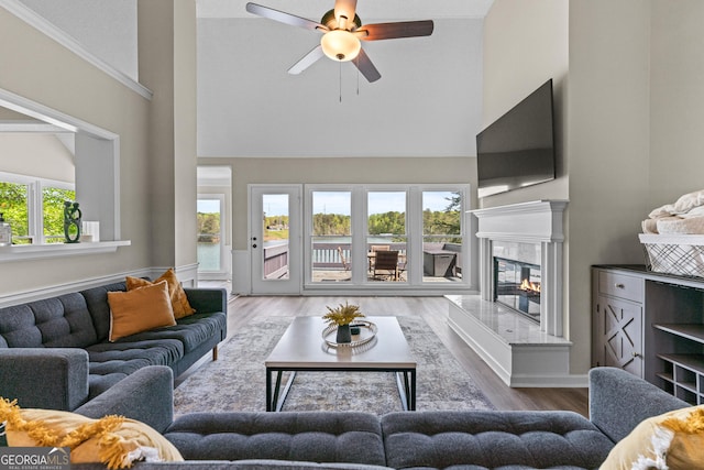 living room with a high end fireplace, wood finished floors, a ceiling fan, and high vaulted ceiling