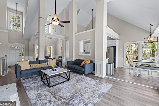 living area with high vaulted ceiling, ceiling fan, a healthy amount of sunlight, and wood finished floors