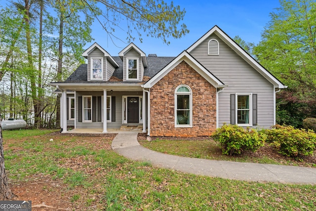 view of front of property featuring stone siding, a front yard, and covered porch