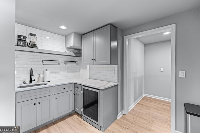 kitchen featuring beverage cooler, open shelves, gray cabinets, a sink, and light wood-style flooring