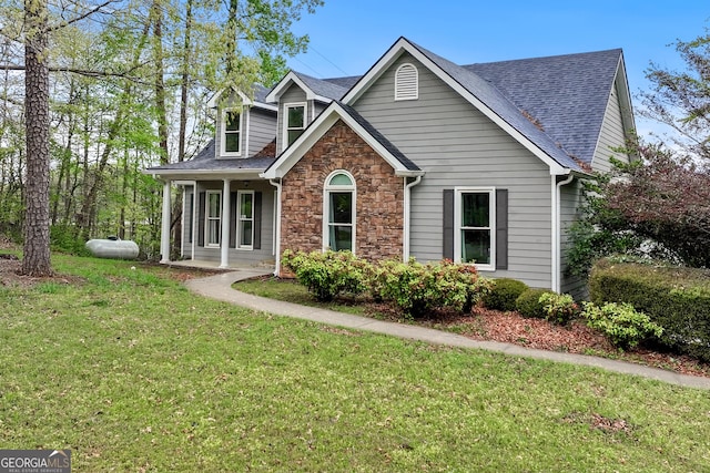 craftsman inspired home featuring roof with shingles, stone siding, and a front lawn