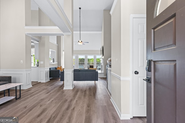 entryway featuring wood finished floors, a ceiling fan, high vaulted ceiling, and a wainscoted wall