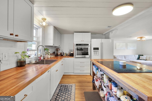 132 4th St, Meldrim, GA 31318 - kitchen with butcher block counters, light wood-type flooring, white cabinets, white appliances, and a sink