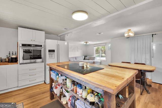 132 4th St, Meldrim, GA 31318 - kitchen featuring freestanding refrigerator, white fridge with ice dispenser, light wood finished floors, stainless steel oven, and black electric stovetop