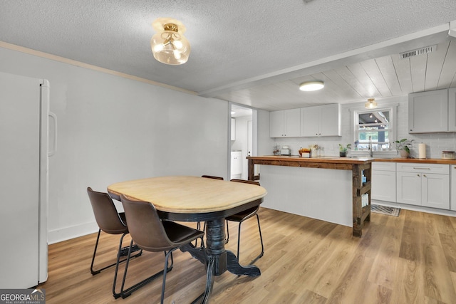 132 4th St, Meldrim, GA 31318 - dining room with light wood-type flooring, visible vents, a textured ceiling, and washer / dryer