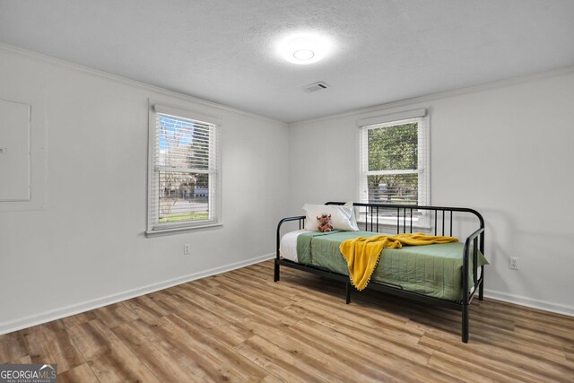 132 4th St, Meldrim, GA 31318 - bedroom with light wood-type flooring, visible vents, electric panel, crown molding, and baseboards