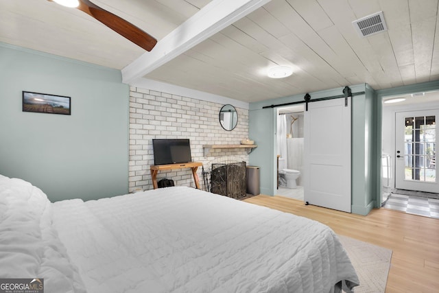 132 4th St, Meldrim, GA 31318 - bedroom featuring wood finished floors, visible vents, beam ceiling, ensuite bathroom, and a barn door