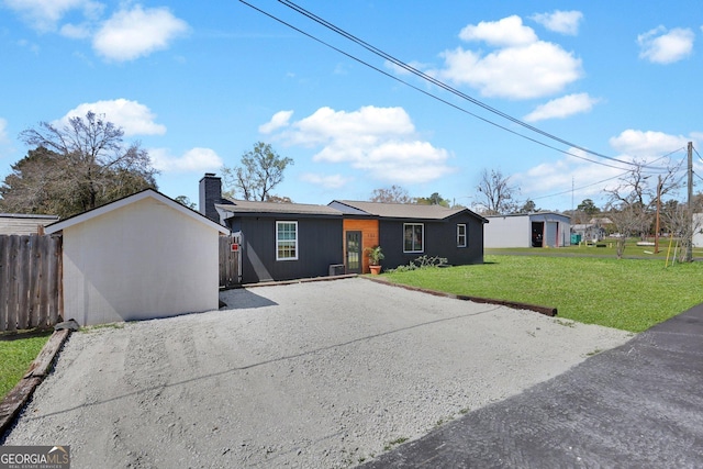 132 4th St, Meldrim, GA 31318 - view of front facade with fence, driveway, a chimney, a front lawn, and an outdoor structure